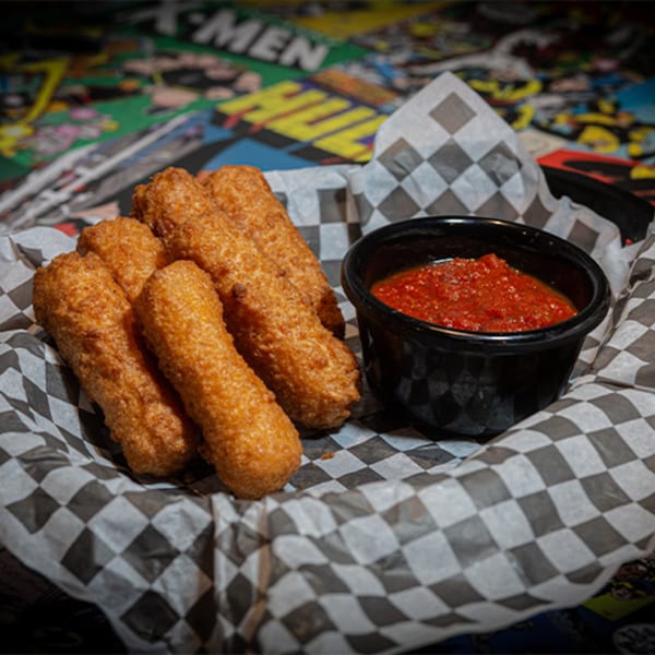 Golden-brown mozzarella sticks and a side of marinara sauce in a checkered paper-lined basket.