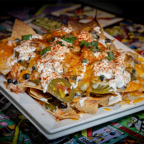 A plate of Black Market Bar and Grill nachos, topped with cheese, sour cream, jalapeños, and spices.