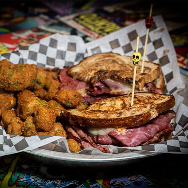A Black Market Bar and Grill pastrami sandwich with fried okra, served in a metal basket.