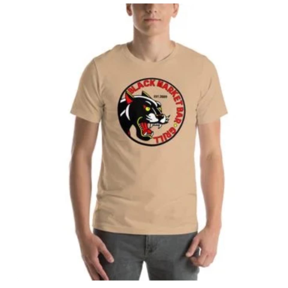Man wearing a tan t-shirt with the Black Market Bar and Grill logo featuring a black panther.
