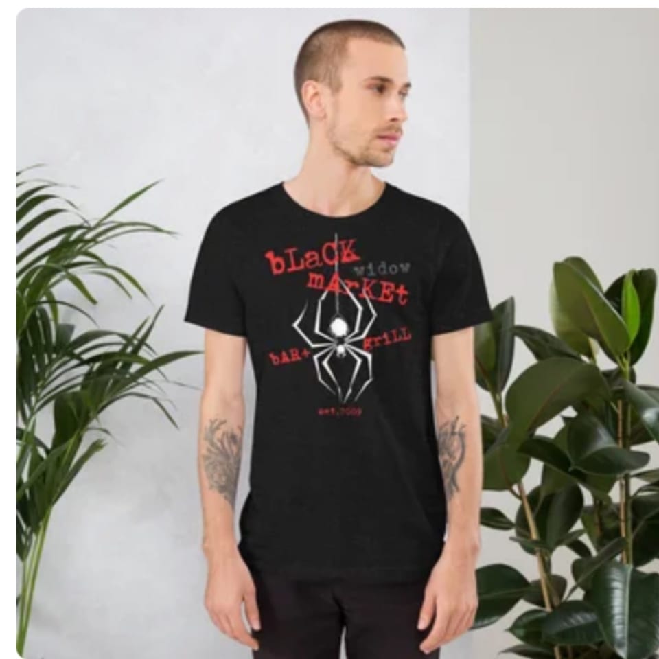 Man wearing a black Black Market Bar and Grill t-shirt with a white spider logo.
