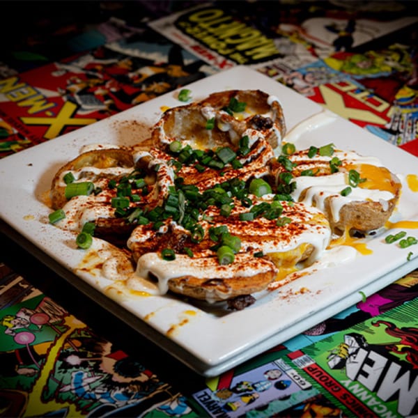 Loaded potato skins with cheese, sour cream, paprika, and green onions on a comic book background.